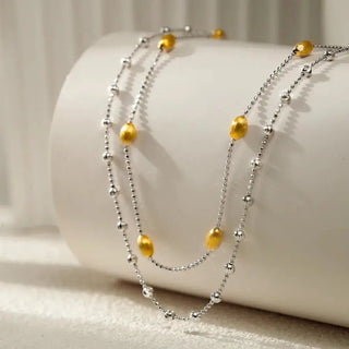 Angled view of the necklace revealing the double-layered design, showing how the brushed nut shell pendant drapes delicately.