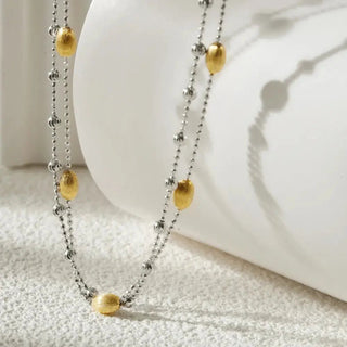 Close-up detail of the nut shell pendant with its soft, brushed surface and finely crafted chain, highlighting the necklace’s refined elegance.