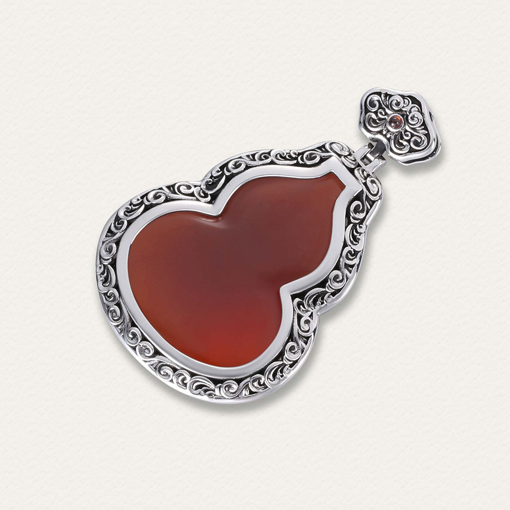 Side angle of the cinnabar gourd pendant highlighting its curved form and silver cap detail.
