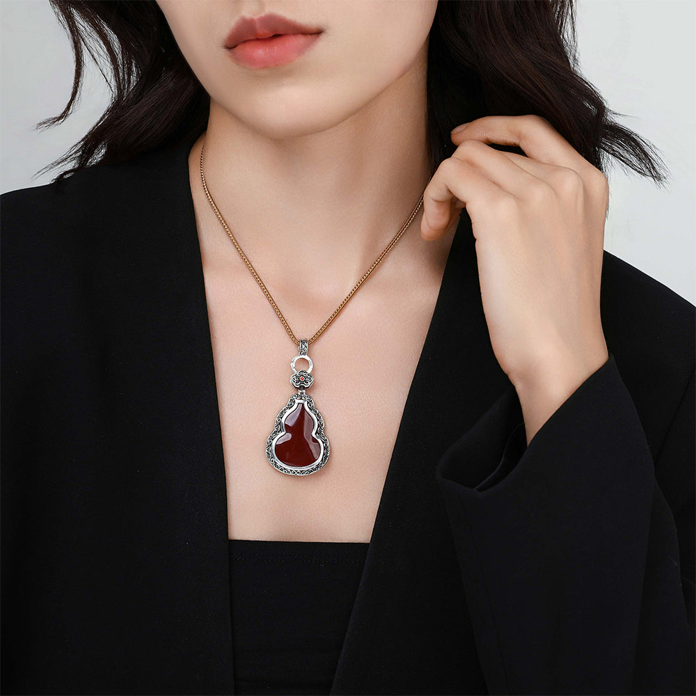 Model wearing the cinnabar gourd pendant necklace layered with other silver jewelry.