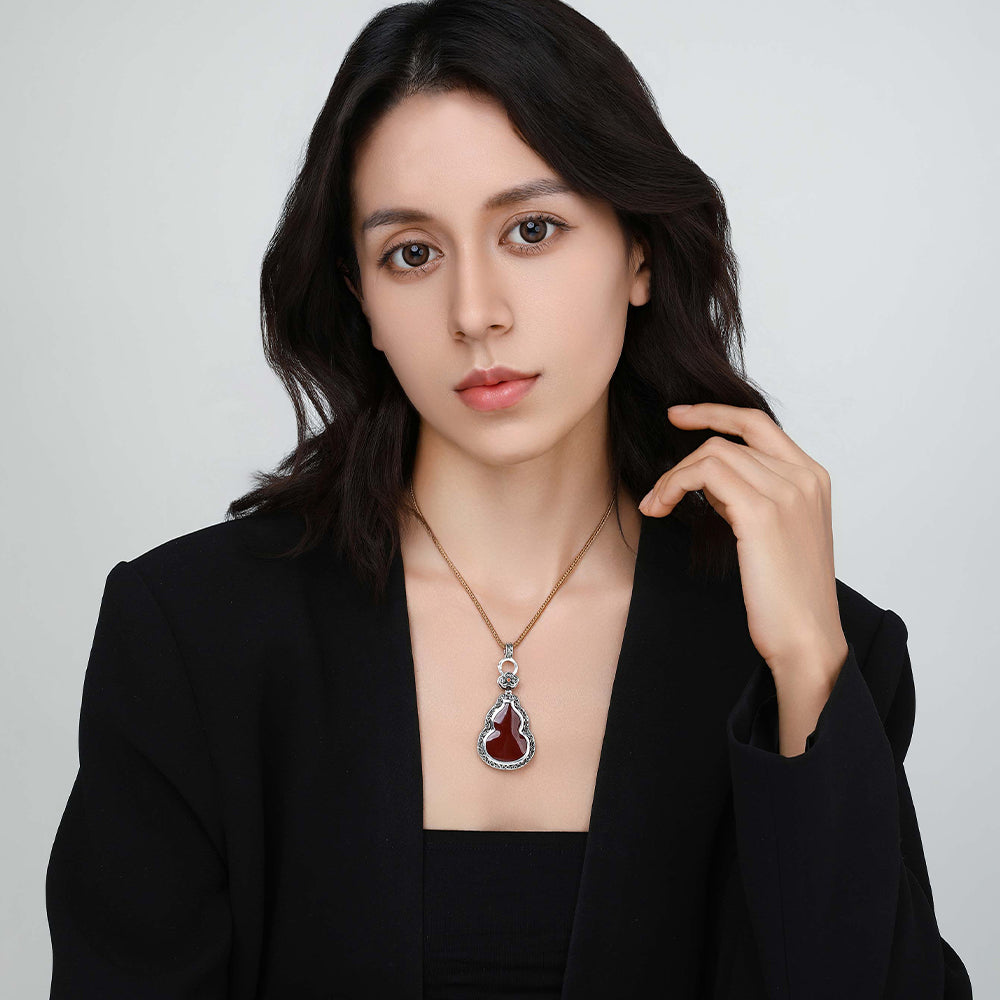 Close-up of model wearing the D-POW cinnabar gourd pendant, showcasing its vibrant red centerpiece.