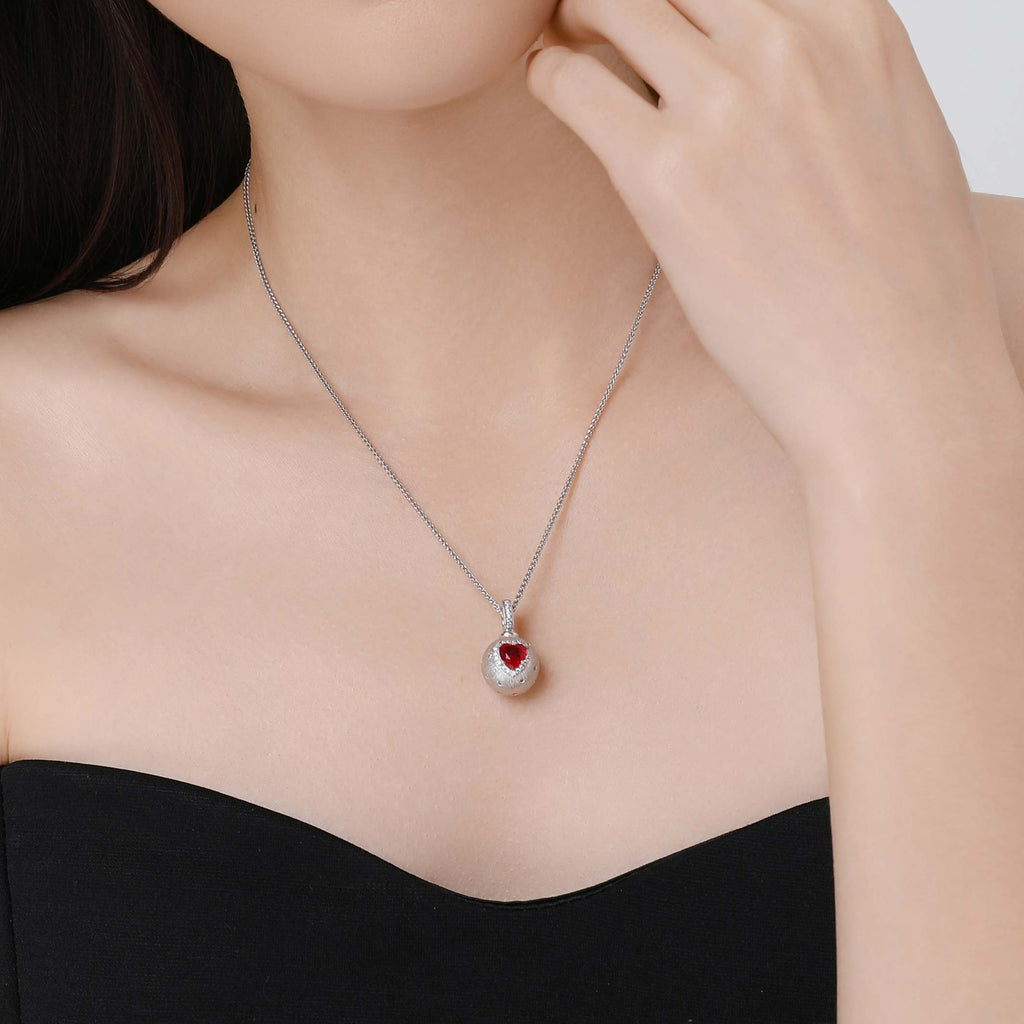 Model wearing the D-POW Cosmic Amour peach motif pendant, showcasing its elegant design as a statement piece of jewelry on the neck.