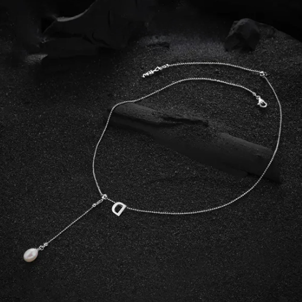 Cream-colored letter "D" pendant on the necklace, focusing on its stylish design and smooth surface.