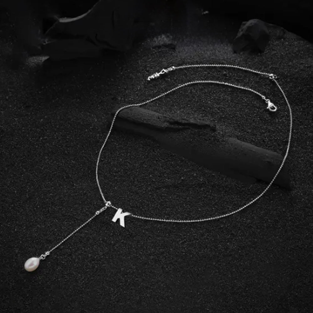 Cream-colored letter "K" pendant, showcased with a sleek and minimalist design.