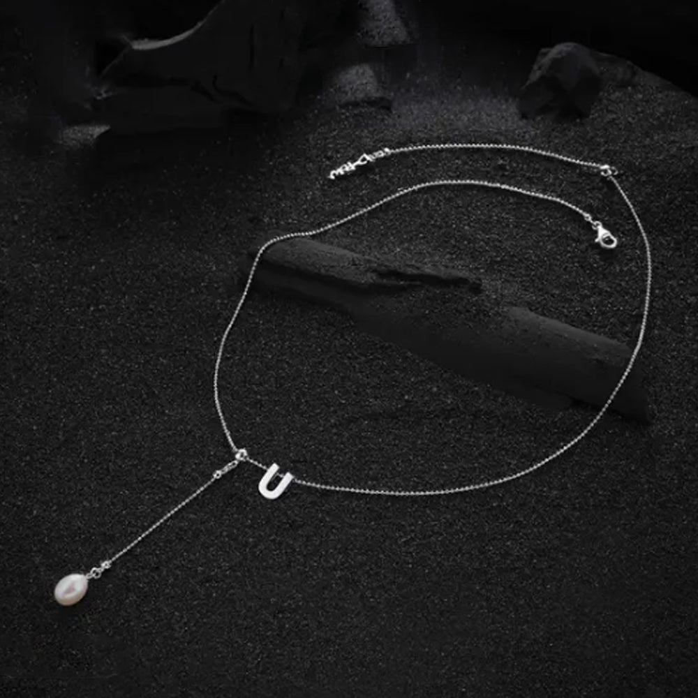 Cream-colored letter "U" pendant, focusing on its sleek and sophisticated design.
