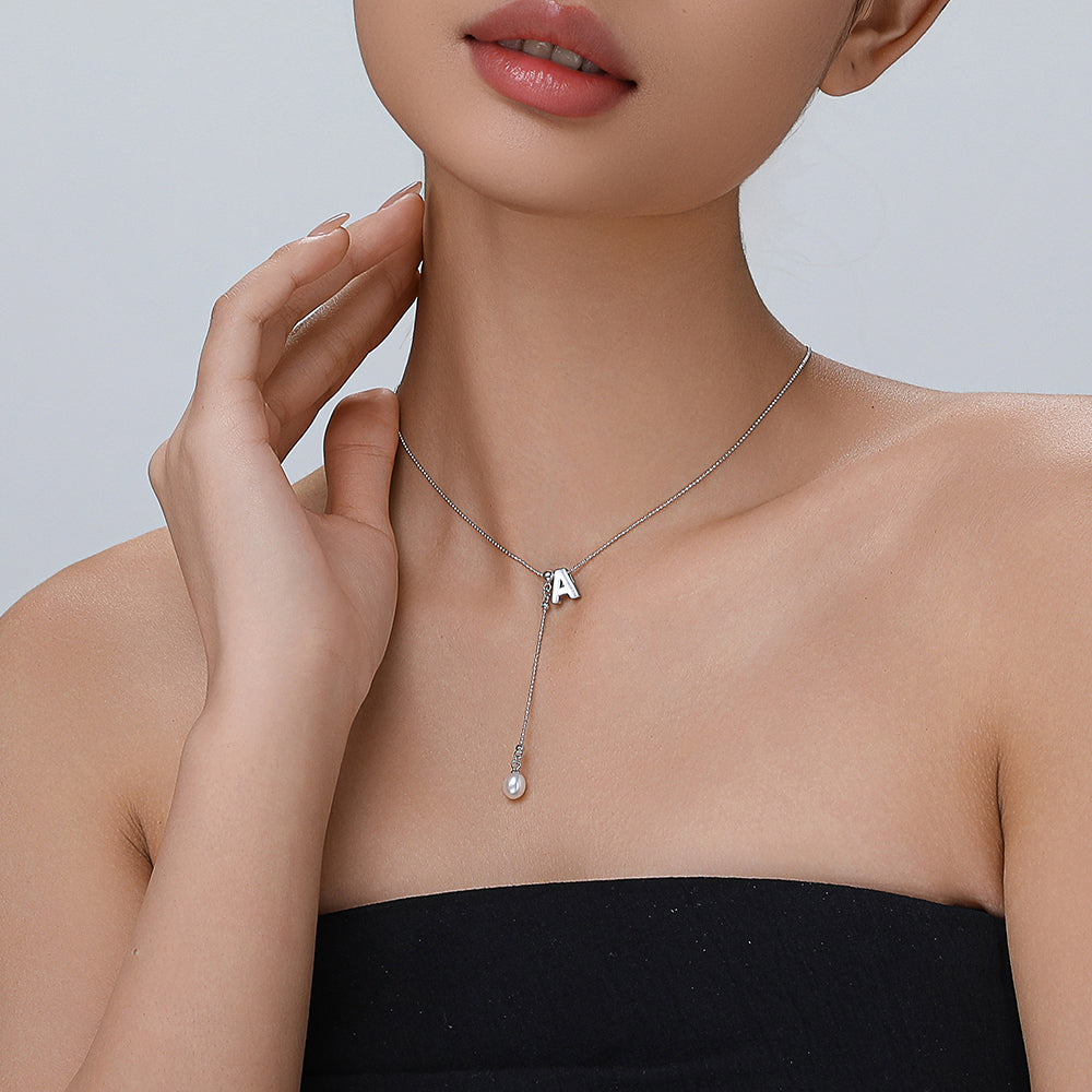 Model wearing the cream-colored letter necklace, showcasing its elegance and style in a chic, casual outfit.