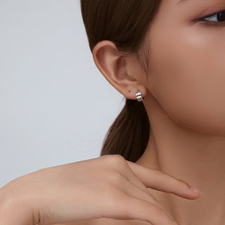 Another angle of the model wearing D-POW hammered sterling silver ear cuffs, highlighting the cuff's fit and stylish appearance on the ear in a chic, everyday setting.