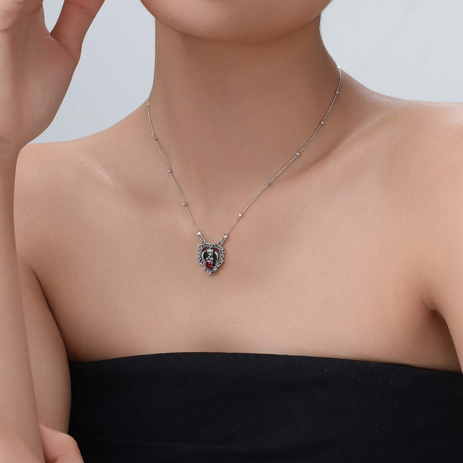 Model wearing the Seraph's Silence red heart necklace, front view highlighting the vivid gemstone and delicate silver chain.